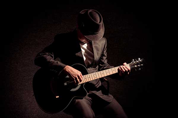musician-playing-the-guitar-on-black-background