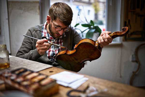 violin-maker-in-his-workshop-varnishing-repaired